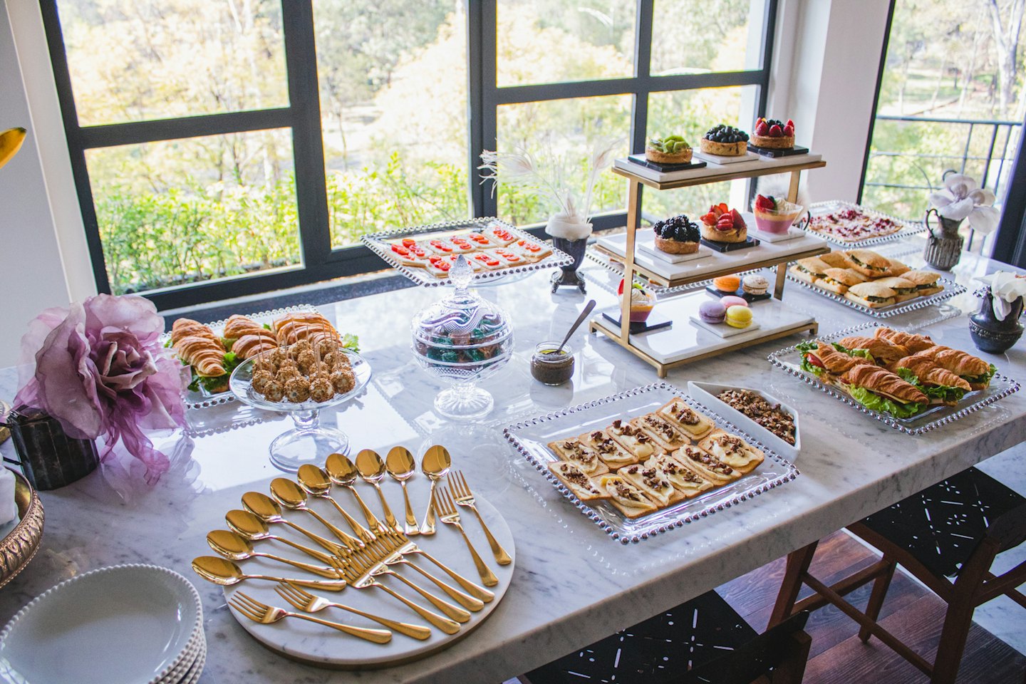 Elegante buffet al chiuso con pasticcini, panini e dolci su marmo.