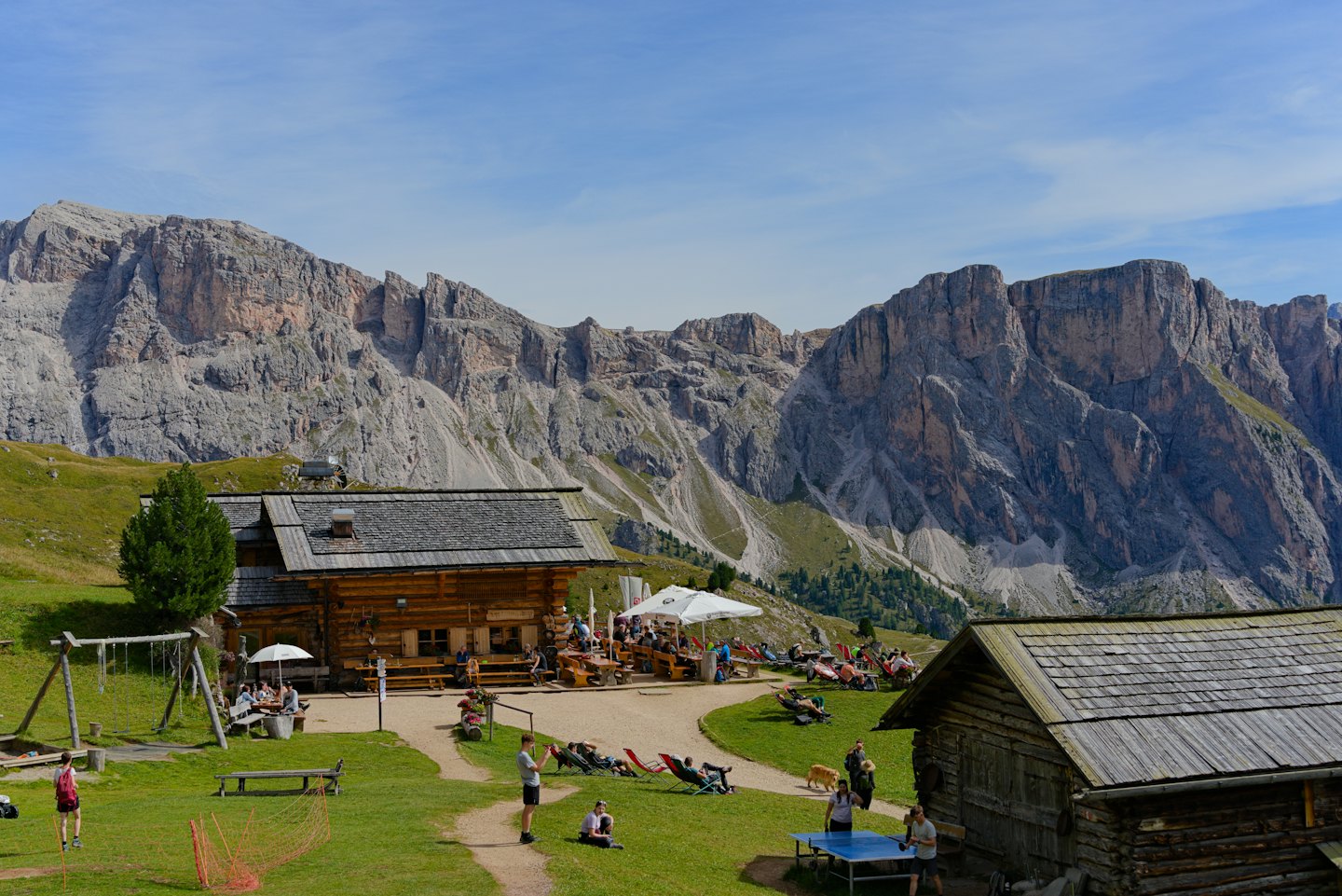 Rifugio di montagna con persone che cenano e giocano a ping-pong.