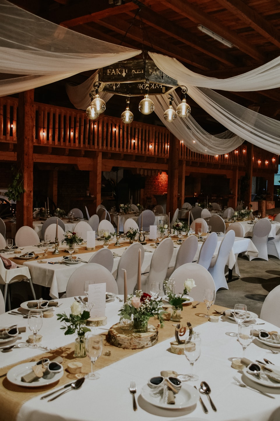 Tavoli decorati con composizioni floreali e luci a filo per un evento rustico.